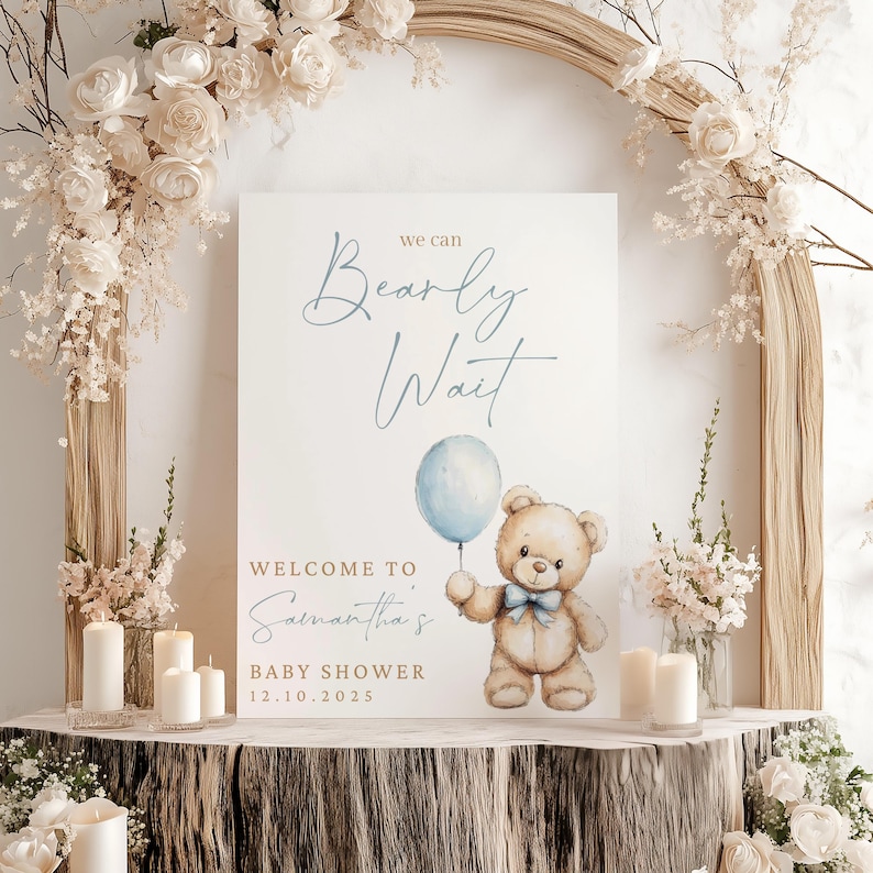 May include: A white sign with the text "We can Bearly Wait" in blue script. Below the text is a cartoon illustration of a brown teddy bear holding a blue balloon. The text "Welcome to Samantha's Baby Shower 12.10.2025" is below the illustration.