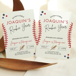 May include: Two baseball-themed birthday invitations for a boy named Joaquin. The invitations are white with red stitching around the edges, and feature a baseball, bat, and stars. The text reads "Let's have a ball at Joaquin's Rookie Year. Please join us to celebrate Joaquin is turning one!" with the date and time of the party.