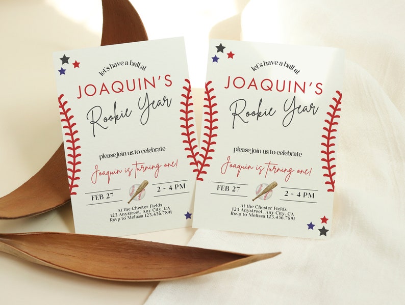 May include: Two baseball-themed birthday invitations for a boy named Joaquin. The invitations are white with red stitching around the edges, and feature a baseball, bat, and stars. The text reads "Let's have a ball at Joaquin's Rookie Year. Please join us to celebrate Joaquin is turning one!" with the date and time of the party.