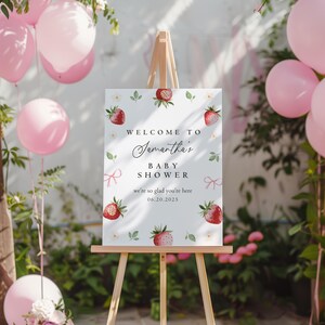 Peut inclure: Panneau d'accueil pour une f&ecirc;te pr&eacute;natale avec un fond blanc et un motif de fraises. Le panneau indique "Bienvenue &agrave; la f&ecirc;te pr&eacute;natale de Samantha, nous sommes ravis de vous accueillir, 06.20.2025".