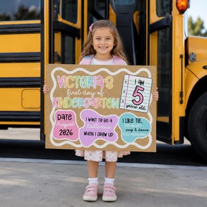 May include: A rectangular sign with a brown background featuring colorful text and shapes. It reads Victoria's first day of Kindergarten, I am 5 years old, Date August 2026, I want to be a Ballerina when I grow up, and I like to sing & dance.