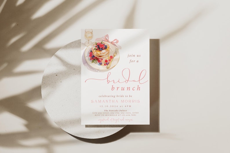 Peut inclure: Une invitation &agrave; un brunch de mariage rose et blanche avec une illustration aquarelle d'une assiette de cr&ecirc;pes, de baies et d'un verre de champagne. Le texte indique "rejoignez-nous pour un brunch de mariage c&eacute;l&eacute;brant la future mari&eacute;e SAMANTHA MORRIS 12.10.2024 &agrave; 16h00 The Passke Palace RSVP &agrave; MICHELLE au 123-436-7891"