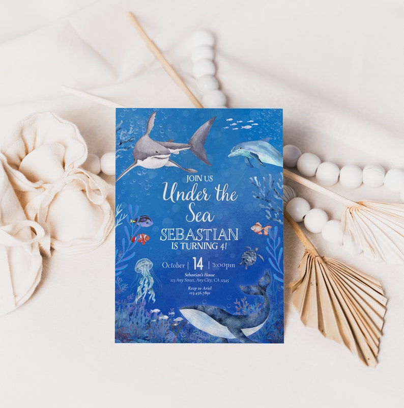 May include: A blue invitation card with an underwater theme. It features illustrations of a shark, dolphin, whale, and various fish. The text reads "Join Us Under the Sea, Sebastian is turning 41" with date and time details.