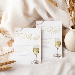 May include: Two white cards with gold text that reads "Pearls and Prosecco" and a watercolor illustration of a glass of champagne and pearls. The cards are bridal shower invitations for Sophia Anderson.