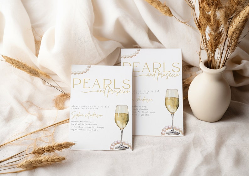 May include: Two white cards with gold text that reads "Pearls and Prosecco" and a watercolor illustration of a glass of champagne and pearls. The cards are bridal shower invitations for Sophia Anderson.
