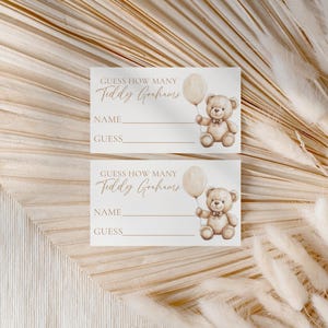 May include: Two rectangular cards with the text "Guess How Many Teddy Grahams" in a script font. Each card features a watercolor illustration of a teddy bear holding a balloon. The cards have lines for "Name" and "Guess".