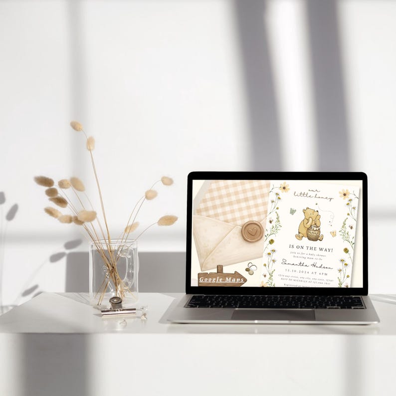 May include: A laptop screen displaying a baby shower invitation with a Winnie the Pooh illustration, honey pot, and floral accents. The text reads our little honey is on the way, Samantha Hudson, 12.10.2024 at 4PM, and Google Maps. An envelope with a wax seal is visible.