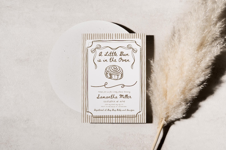 May include: A baby shower invitation card with the text "A Little Bun is in the Oven" in a decorative frame. The card has a striped background and a drawing of a bun. The invitation is for Samantha Miller.