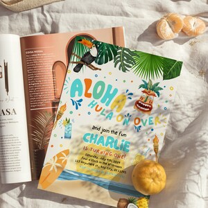 May include: A colorful invitation for a luau themed first birthday party. The invitation features a toucan, a tiki mask, and the text "Aloha Hula On Over and join the fun Charlie is turning one!"  The invitation also includes the date, time, and location of the party.
