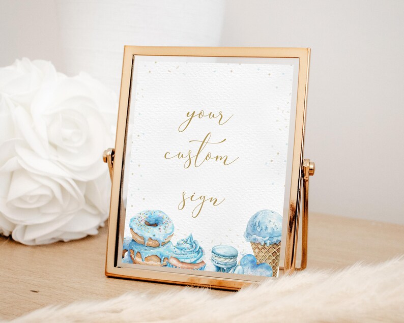 May include: Gold framed sign with the text "your custom sign" in gold lettering. The sign features watercolour illustrations of blue doughnuts, a blue ice cream cone, and blue macarons.
