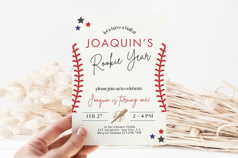 May include: Baseball-themed birthday party invitation with red stitching around the edges, a baseball bat and ball, and the text "Let's have a ball at Joaquin's Rookie Year. Please join us to celebrate Joaquin is turning one! Feb 27, 2-4 PM. At the Chester Fields, 123 Anystreet, Any City, CA. RSVP to Melissa 123.456.7891."