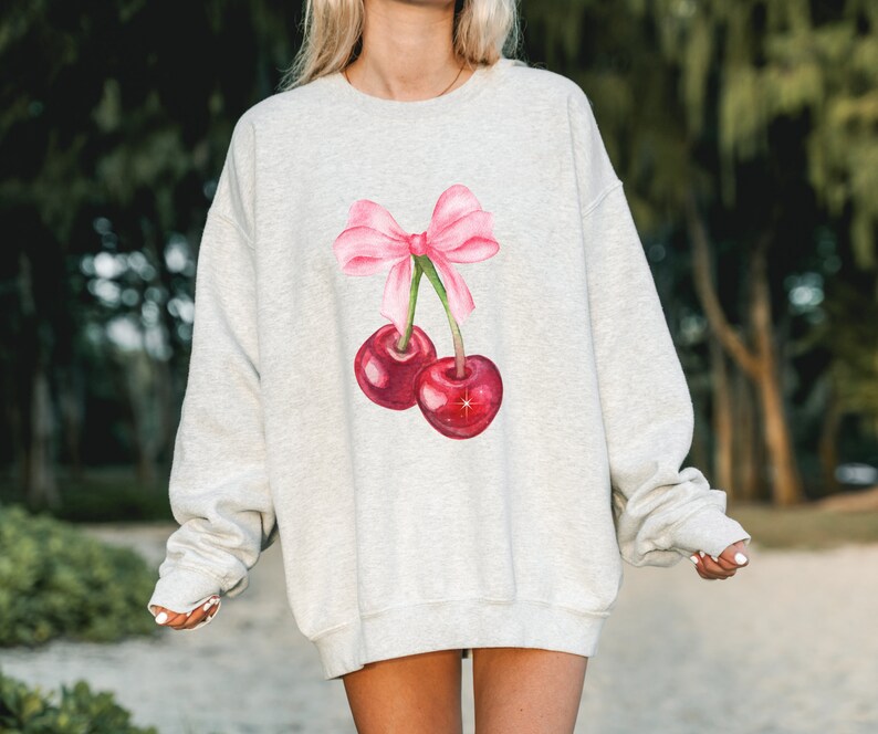 May include: A gray sweatshirt with a pink bow and two red cherries printed on the front.