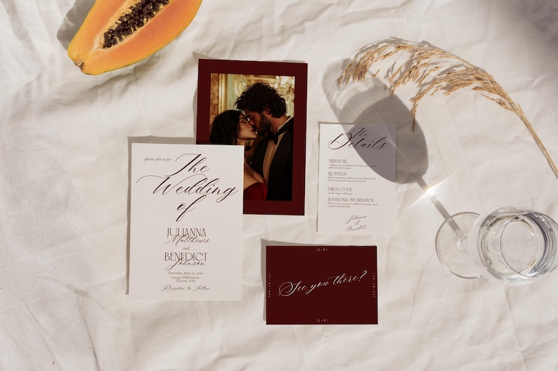 May include: Wedding invitation suite featuring a photo of a couple kissing, a menu card, and a card that says "See you there?" The invitation reads "The Wedding of Julianna Matthews and Benedict Johnson". The suite is on a white surface.