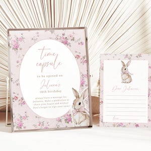 May include: Pink floral time capsule sign with a bunny illustration and the text "Time capsule to be opened on Julianna's 18th birthday. Please leave a message for Julianna. Make a prediction or share your hopes and wishes! Don't forget to sign your name."