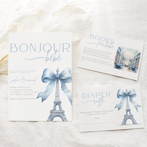 May include: A baby shower invitation featuring a blue and white Eiffel Tower design. The invitation reads "Bonjour B&eacute;b&eacute;" and includes the text "Please join us for a baby shower in honour of..." and "Saturday, October 15, 2023..."