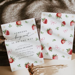 May include: A baby shower invitation with a watercolor strawberry pattern. The invitation reads "Someone berry sweet is on the way" and includes details for the shower honoring Olivia Swanson.