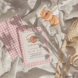 Puede incluir: Una invitaci&oacute;n de baby shower en gingham rosa y blanco con una linda ilustraci&oacute;n de pastel y el texto "A Little Cutie Pie Is On The Way!"  Samantha Jackson 04 de octubre de 2024 a las 3 PM.