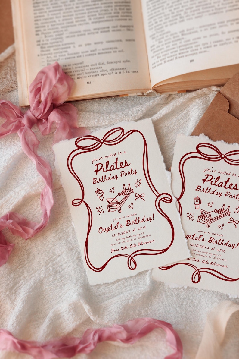 May include: Two cream-colored Pilates birthday party invitations with a burgundy border and text. The invitations feature illustrations of Pilates equipment and text that reads "Crystal's Birthday!" and "Dress Code: Cute Activewear."