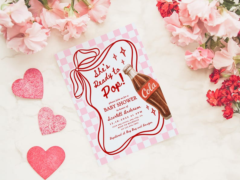 Puede incluir: Una invitaci&oacute;n a un baby shower con un dise&ntilde;o retro. La invitaci&oacute;n presenta un fondo a cuadros rojos y blancos, un contorno rojo y el texto "She's Ready to Pop!". Se incluye una ilustraci&oacute;n de una botella de cola. Decoraciones en forma de coraz&oacute;n rosa y flores rodean la invitaci&oacute;n.