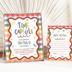 Puede incluir: Un letrero enmarcado y una tarjeta a juego con un fondo de cuadros arco&iacute;ris y un borde marr&oacute;n ondulado. El letrero dice Time Capsule to be opened on Timothy's 18th birthday. La tarjeta dice Dear Timothy con l&iacute;neas para escribir un mensaje.