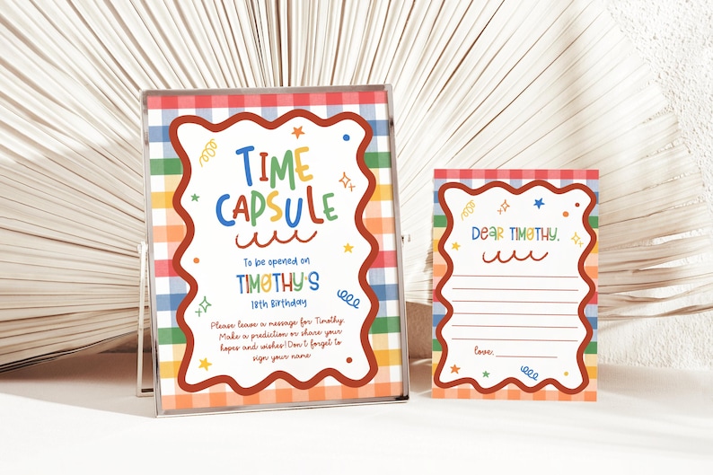 Puede incluir: Un letrero enmarcado y una tarjeta a juego con un fondo de cuadros arco&iacute;ris y un borde marr&oacute;n ondulado. El letrero dice Time Capsule to be opened on Timothy's 18th birthday. La tarjeta dice Dear Timothy con l&iacute;neas para escribir un mensaje.