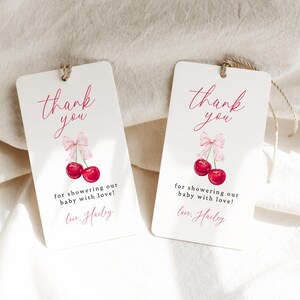 May include: Two white thank you tags with pink and red cherries and the text "thank you" and "for showering our baby with love! Love, Hailey".