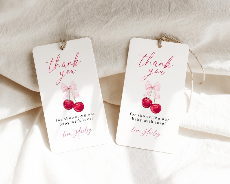 May include: Two white thank you tags with pink and red cherries and the text "thank you" and "for showering our baby with love! Love, Hailey".