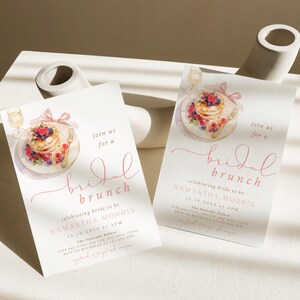 Peut inclure: Deux invitations de couleur rose et blanche pour un brunch de mariage avec une illustration aquarelle d'une assiette de cr&ecirc;pes avec des baies et un verre de champagne. Le texte sur les invitations indique "rejoignez-nous pour un brunch de mariage c&eacute;l&eacute;brant la future mari&eacute;e Samantha Morris".