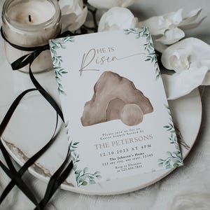 May include: A white card with green foliage border and a watercolor illustration of a stone tomb with a rolling stone. The text "He is Risen" is written in brown script. The card is an invitation to an Easter brunch hosted by The Petersons on December 10, 2025 at 4 PM at The Johnson's Home. The address and RSVP information are included.