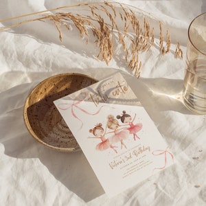 May include: A pink and gold invitation card with a watercolor illustration of three ballerinas. The text on the card reads "Victoria is Tutu Cute" and "Please join us to celebrate Victoria's 2nd Birthday, October 04, 2024 at 3PM."