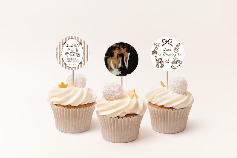 Peut inclure: Trois cupcakes avec gla&ccedil;age blanc, chacun surmont&eacute; d'un &eacute;l&eacute;ment d&eacute;coratif. L'un pr&eacute;sente une photo d'un couple, un autre un topper "Bridal Shower", et le dernier dit "Love is Brewing".