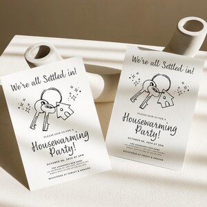 K&ouml;nnte beinhalten: Zwei schwarz-wei&szlig;e Einladungen zu einer Einweihungsfeier mit einer Schl&uuml;ssel- und Haus-Illustration. Der Text auf den Einladungen lautet "We're all settled in!" und "Please join us for a Housewarming Party!" Das Datum und die Uhrzeit der Party sind mit "October 04, 2024 at 3PM" angegeben.