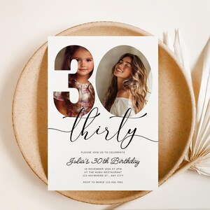 May include: A white invitation card with a black and white photo of two women. The number 30 is cut out of the card and the women's faces are visible through the cutouts. The text "thirty" is written in cursive script below the number. The invitation text reads "Please join us to celebrate Julia's 30th Birthday" and includes the date, time, location, and RSVP information.
