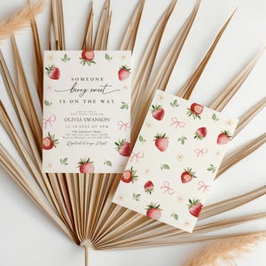 May include: A baby shower invitation with a strawberry pattern. The invitation reads "Someone berry sweet is on the way" and includes the name Olivia Swanson, the date 12.10.2024 at 4PM, and the location "The Johnson's Home".