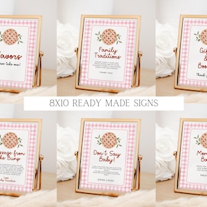 Puede incluir: Carteles dorados con bordes de cuadros rosas y textos como "Favors" y "Family Traditions". Cada cartel, con un gr&aacute;fico de tarta, est&aacute; dise&ntilde;ado para un baby shower. El texto "8X10 READY MADE SIGNS" tambi&eacute;n es visible.