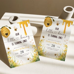 May include: Two yellow and white bee-themed first birthday party invitations with a honeycomb design, dripping honey, and a floral background. The text on the invitations reads "Our little honey is turning one!" and "Emilia's 1st Bee-Day!" with the date and time of the party.