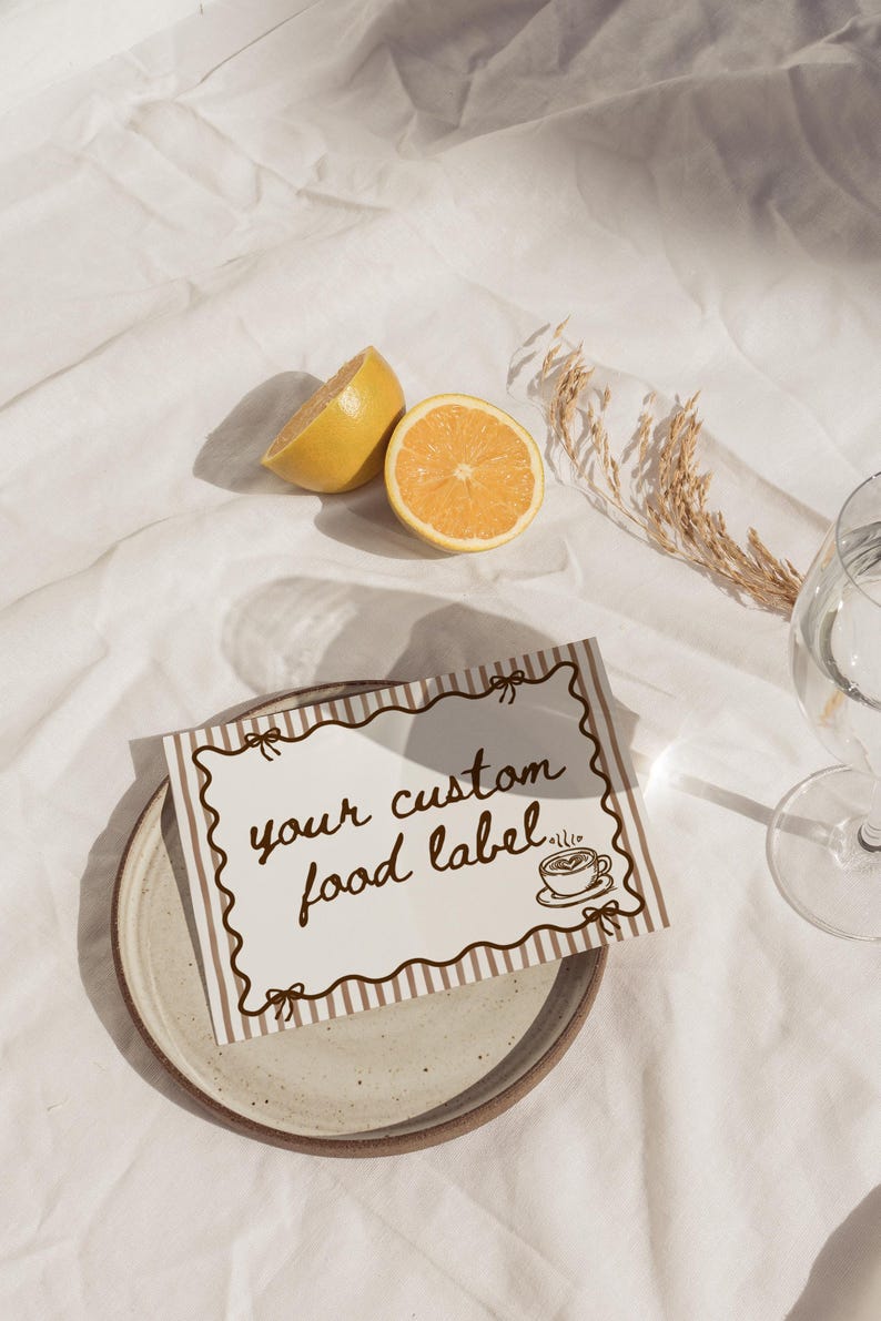 Peut inclure: Une tasse en c&eacute;ramique blanche avec une anse noire et l'inscription "But First, Coffee" en noir, dans une police manuscrite. La tasse est pos&eacute;e sur une surface blanche.