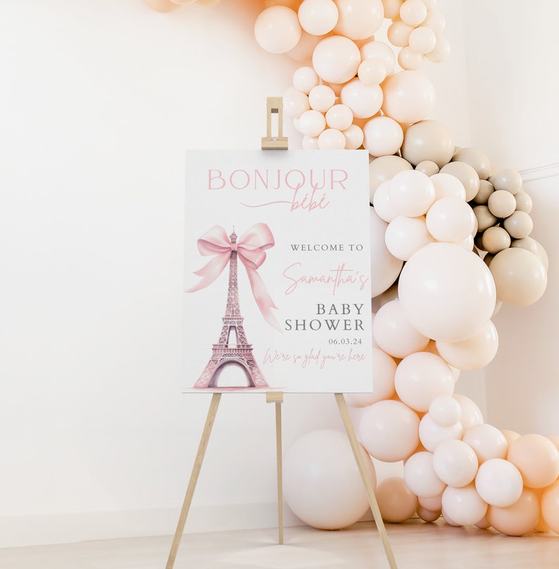 Puede incluir: Un cartel de bienvenida para una baby shower rosa y blanco con una ilustraci&oacute;n de acuarela de la Torre Eiffel y un lazo rosa. El cartel dice "Bonjour bebe, Bienvenida a la baby shower de Samantha, 06.03.24, Estamos encantados de que est&eacute;s aqu&iacute;."