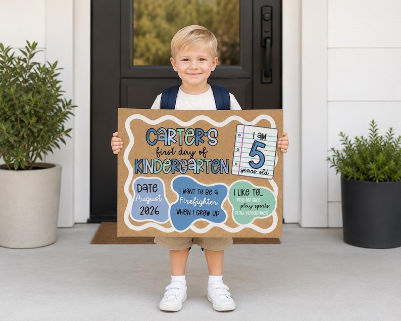 May include: A rectangular sign made of brown paper with a white scalloped border, featuring the text Carter's first day of Kindergarten, I am 5 years old, Date August 2026, I want to be a Firefighter, and I like to play sports and play videogames.