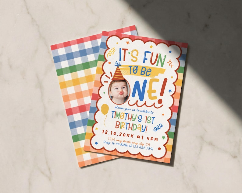 Puede incluir: Una tarjeta de invitaci&oacute;n de cumplea&ntilde;os rectangular con un borde blanco festoneado, una foto de un ni&ntilde;o con gorro de fiesta y texto colorido que dice IT'S FUN TO BE ONE! TIMOTHY'S 1ST BIRTHDAY! 12.10.20XX at 4PM. El reverso tiene un patr&oacute;n de cuadros.