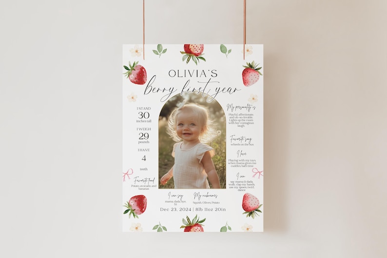 May include: A white and pink printable first birthday poster with a strawberry theme. The poster features a photo of a baby girl, along with details about her first year, including her height, weight, and favorite things. The text on the poster reads "Olivia's Berry First Year" and includes the date "Dec 23, 2024".