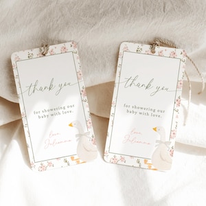 May include: Two white thank you tags with pink floral designs and a cartoon goose illustration. The text on the tags reads "thank you for showering our baby with love." and "Love, Julianna".