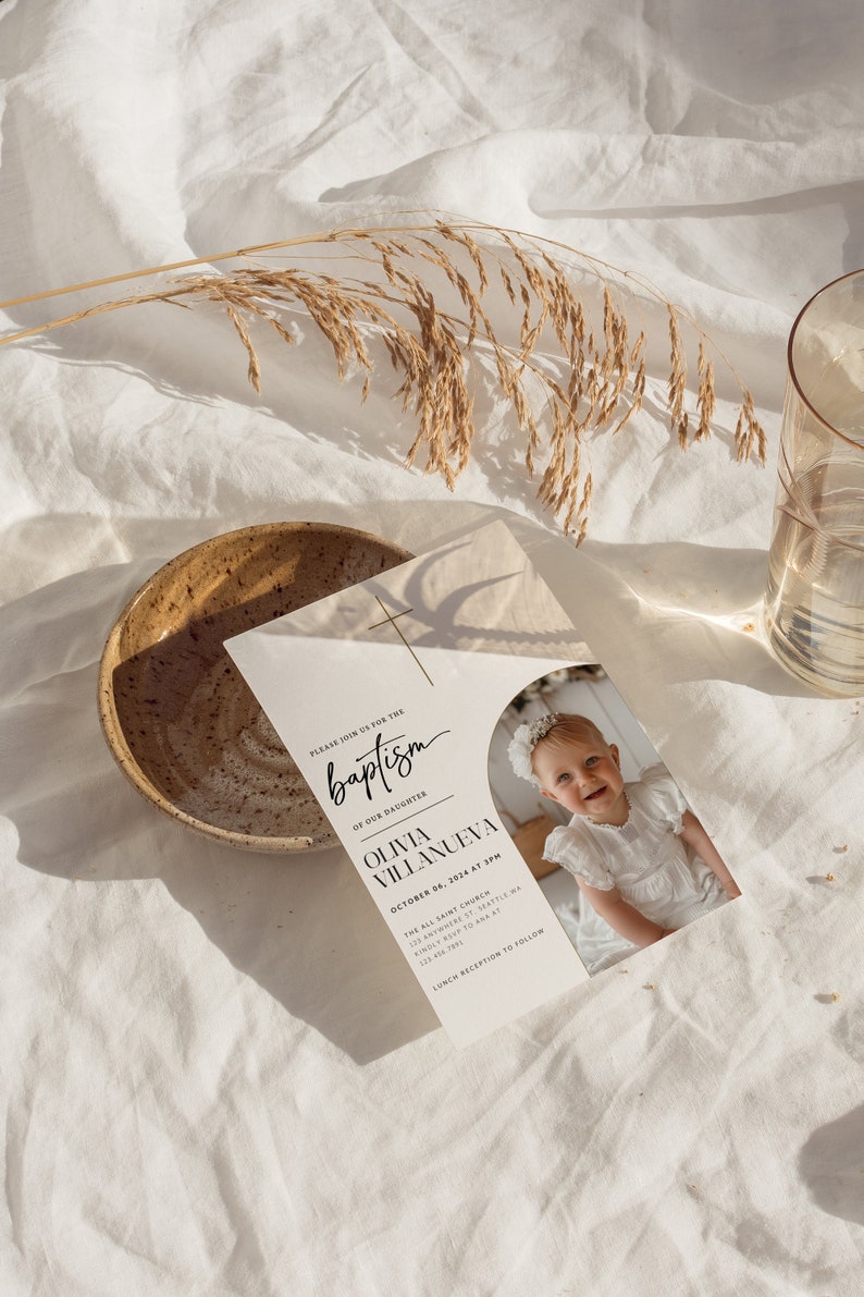May include: A white baptism invitation with a photo of a baby girl in a white dress. The invitation includes the text "Please join us for the baptism of our daughter Olivia Villanueva, October 06, 2024 at 3PM, The All Saint Church, 123 Anywhere St. Seattle WA, Kindly RSVP to Ana at 1234567890, Lunch Reception to Follow."