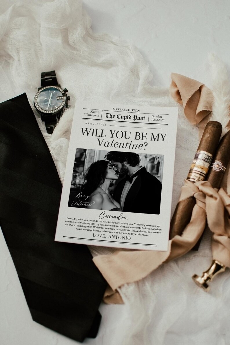 May include: A Valentine's Day card with the text "Will You Be My Valentine?" and a photo of a kissing couple. The card is accompanied by a black watch, a black tie, and two cigars.