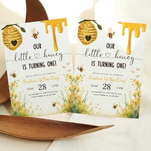May include: A yellow and white bee-themed first birthday party invitation with a honeycomb, dripping honey, and the text "Our little honey is turning one!" and "Emilia's 1st Bee-Day!"