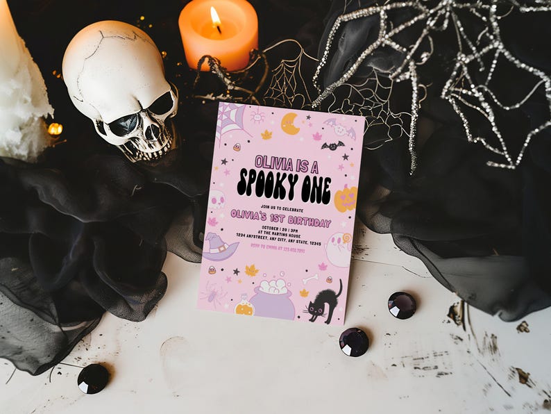 Puede incluir: Invitaci&oacute;n a una fiesta de Halloween rosa y naranja con el texto "Olivia is a Spooky One" y "Olivia's 1st Birthday". La invitaci&oacute;n presenta un sombrero de bruja, un caldero, un gato negro y otras ilustraciones de tem&aacute;tica de Halloween.