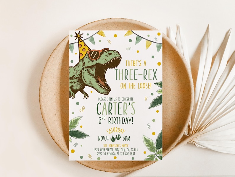 May include: A birthday party invitation featuring a green dinosaur wearing sunglasses and a party hat. The text reads "There's a Three-Rex on the Loose!" and invites guests to Carter's 3rd birthday on November 4th at 3 PM.
