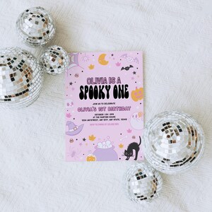 Puede incluir: Invitaci&oacute;n a una fiesta de Halloween rosa con el texto "Olivia is a Spooky One" y "Olivia's 1st Birthday". La invitaci&oacute;n presenta un gato negro, un sombrero de bruja, un caldero y otras ilustraciones con tem&aacute;tica de Halloween.