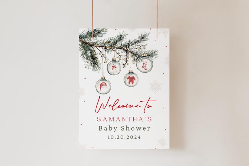 K&ouml;nnte beinhalten: Ein wei&szlig;es Willkommensschild mit rotem Text, auf dem steht "Willkommen zu Samanthas Baby Shower 10.20.2024". Das Schild zeigt eine Aquarell-Illustration eines Kiefernzweigs mit Ornamenten. Die Ornamente sind aus klarem Glas mit roten und wei&szlig;en Illustrationen einer Baby-M&uuml;tze, eines Baby-Bodys, einer Baby-Socke und einer Schleife.