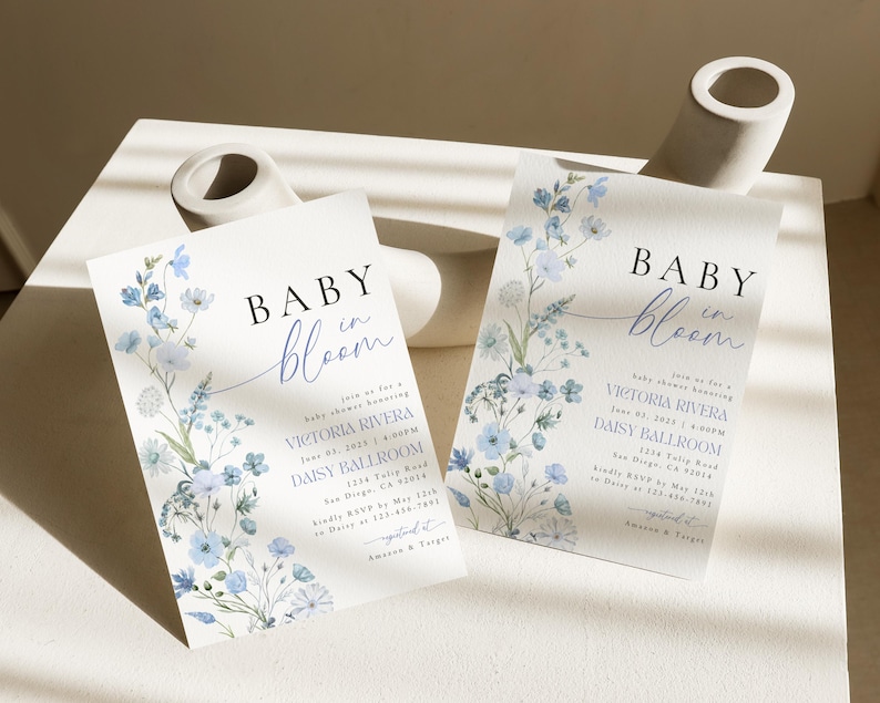 Puede incluir: Invitaci&oacute;n a una fiesta de bienvenida al beb&eacute; con flores azules y blancas, con el texto "Baby in Bloom" y los detalles del evento, incluyendo la fecha, la hora y el lugar.
